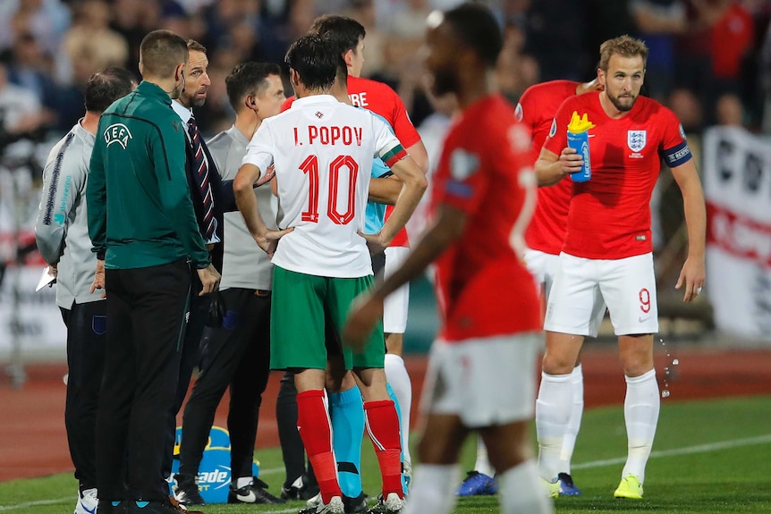 A team manager talks to a referee after an international game is halted because of racist abuse.