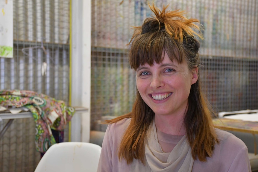 A young lady with blue eyes and brown hair smiles at the camera.