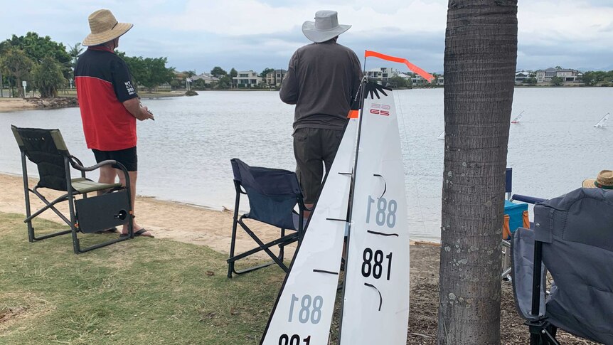 Two members of paradise Radio Yacht Club with remotes watching on during a race at Emerald Lakes