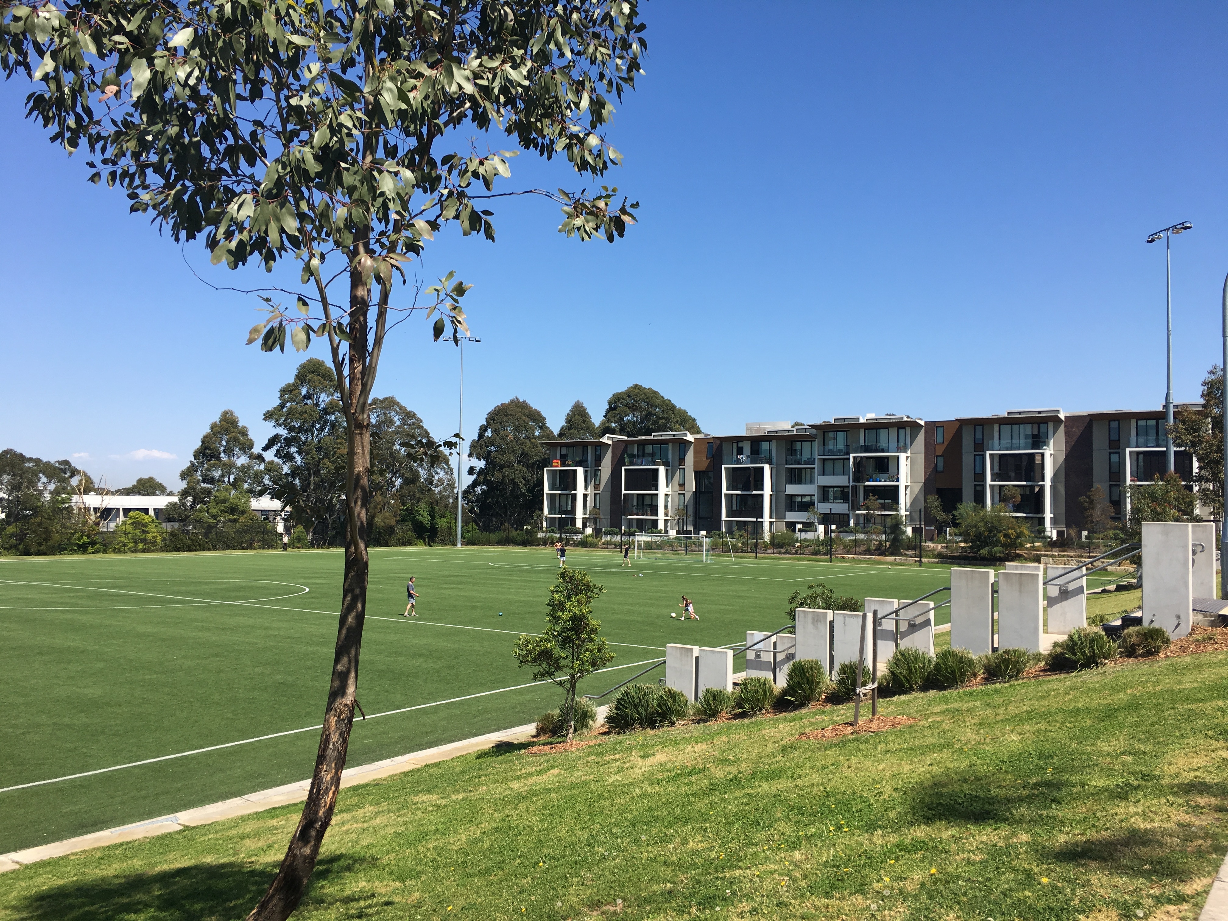 Los futbolistas juegan en un campo de césped artificial verde entre apartamentos
