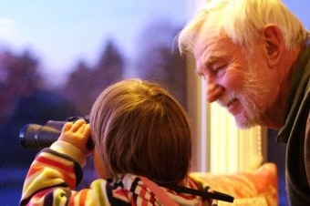 An older man looks at a young child.