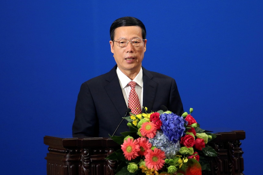 Chinese Vice-Premier Zhang Gaoli makes a speech in front of a podium covered with flowers.