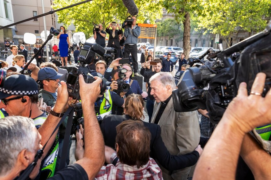 George Pell is surrounded by cameras and police as he walks into the County Court in Melbourne.
