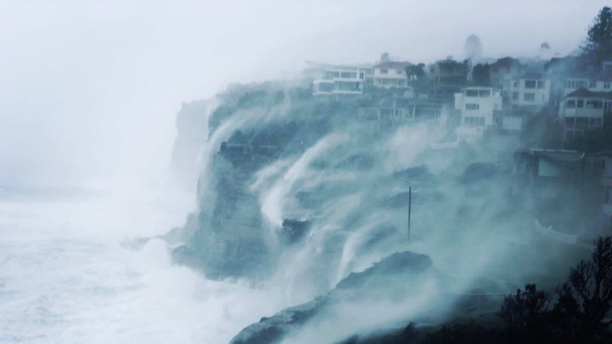 Huge waves and sea spray washes over a group of clifftop homes at Vaucluse in Sydney's east