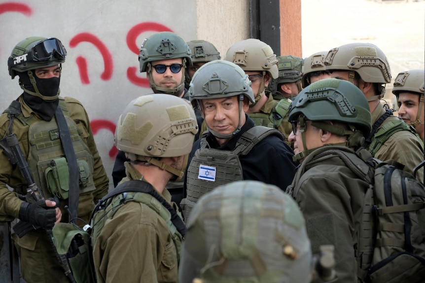 Israeli Prime Minister Benjamin Netanyahu wears a protective vest and helmet while seeing troops.