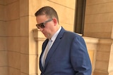 Daniel Symons walks outside court with his head bowed.