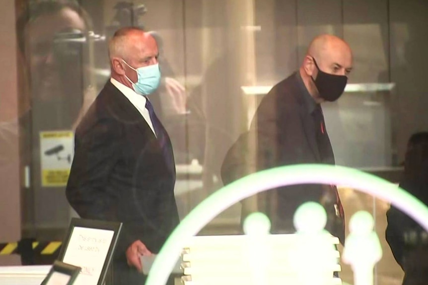 Two men wearing face masks inside a building