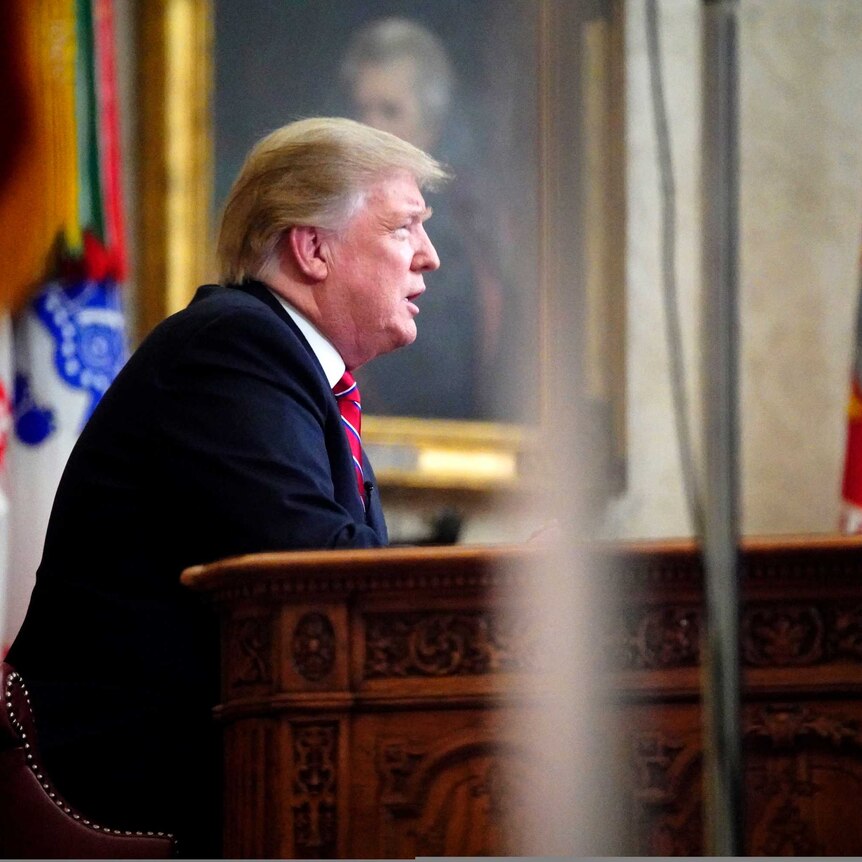 A side on view of Donald Trump sitting at a desk