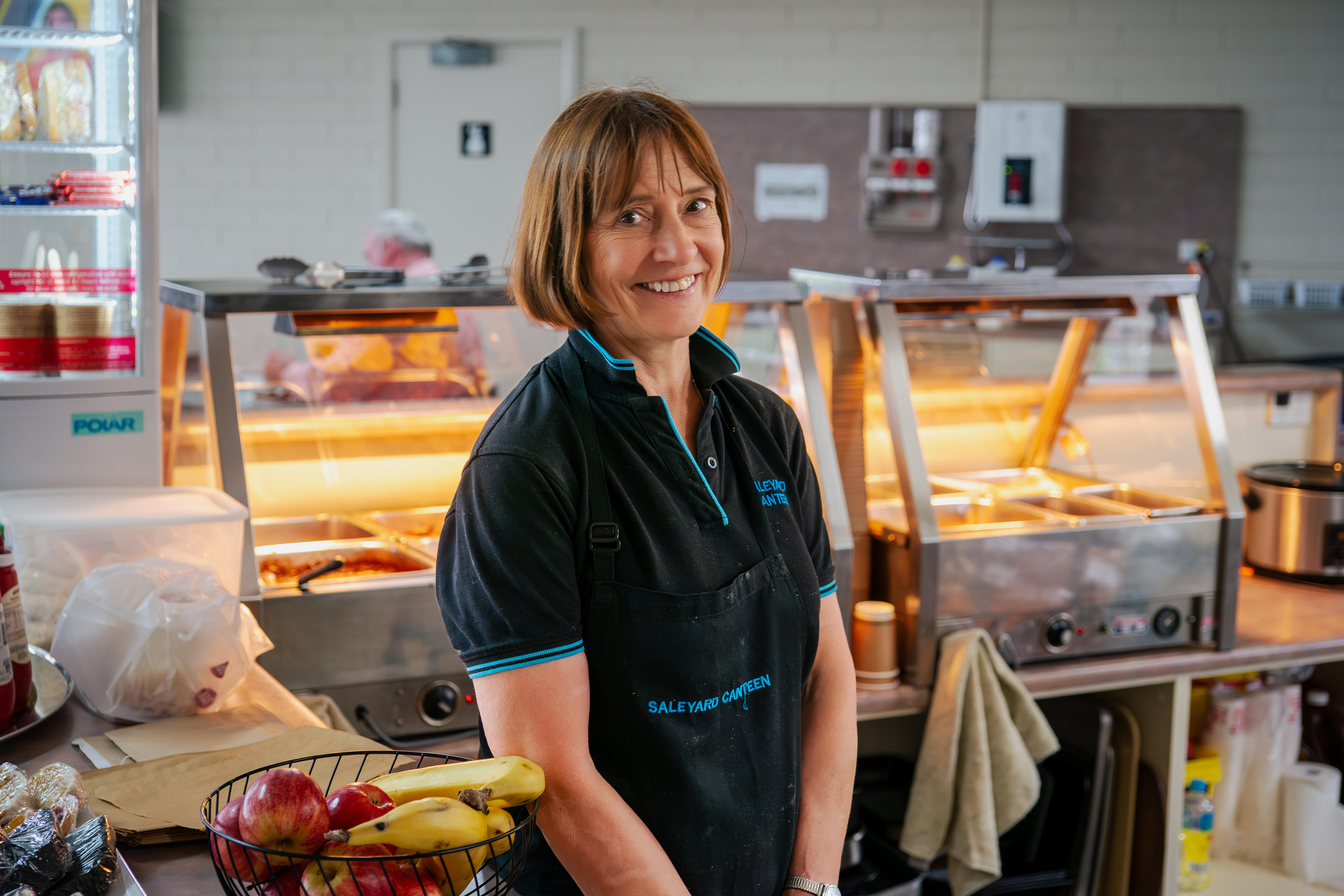 Una mujer sonríe en una cocina comercial. 