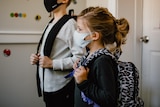Two children weariing a mask and carrying backpacks