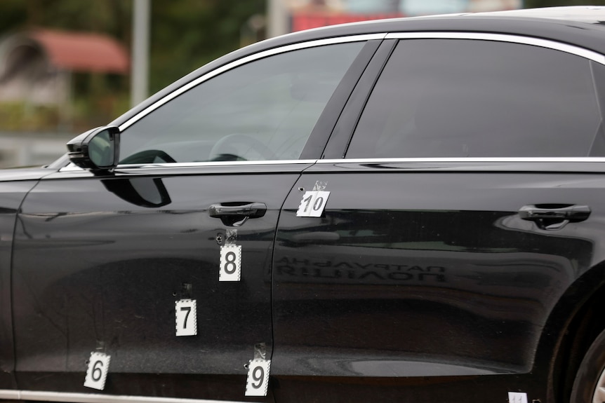 Markers are attached next to bullet holes in a car