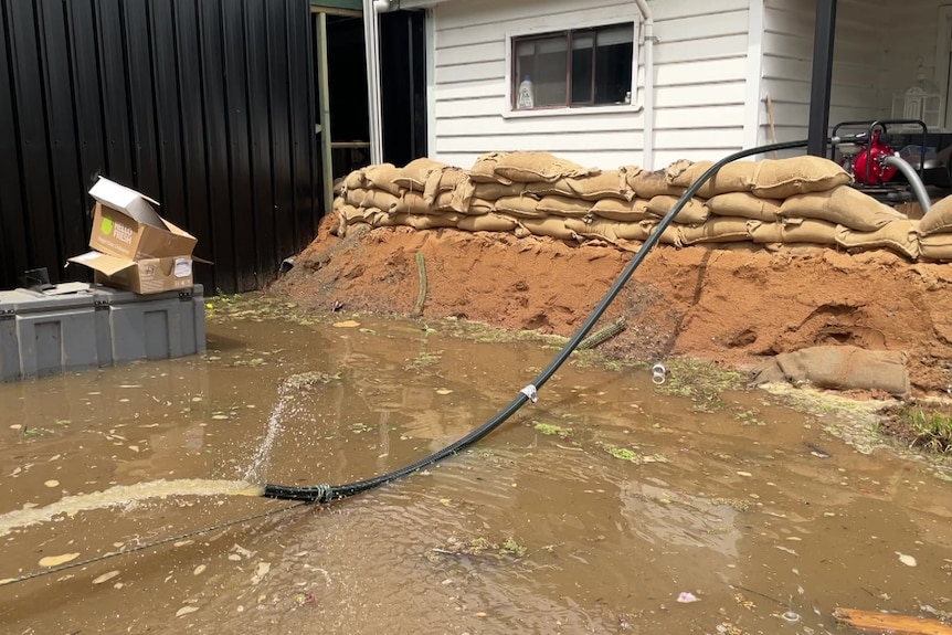 A man and woman leading on a wall of sandbags in front of their home