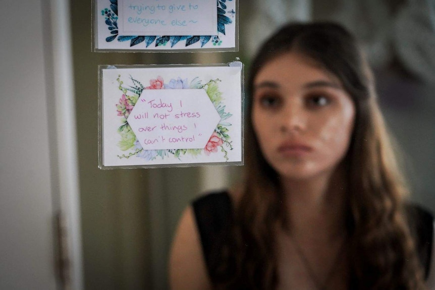Shannon Nicholls looks at a mirror with positive affirmation notes attached to it.