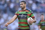 Greg Inglis points at the ground with the ball under his other arm