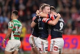 A group of rugby league players embrace after winning a match