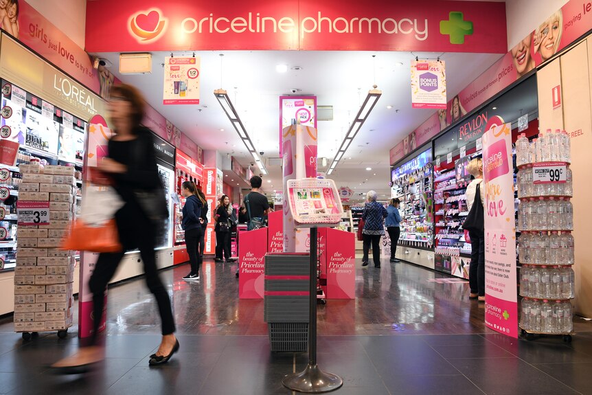 A blurry woman walks out of a Priceline Pharmacy.