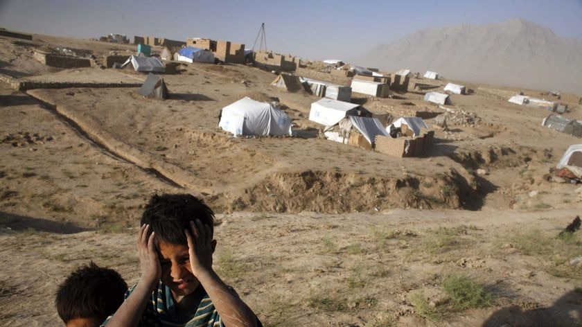 Afghan refugee children stand on the barren, dusty plains in Barikab, Afghanistan