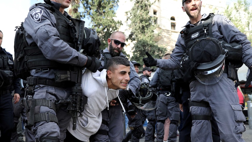Israeli policemen detain a Palestinian protestor
