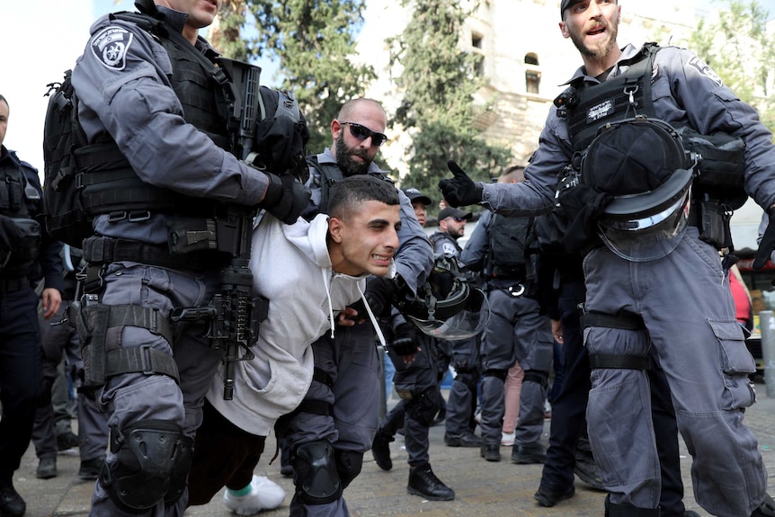Israeli policemen detain a Palestinian protestor