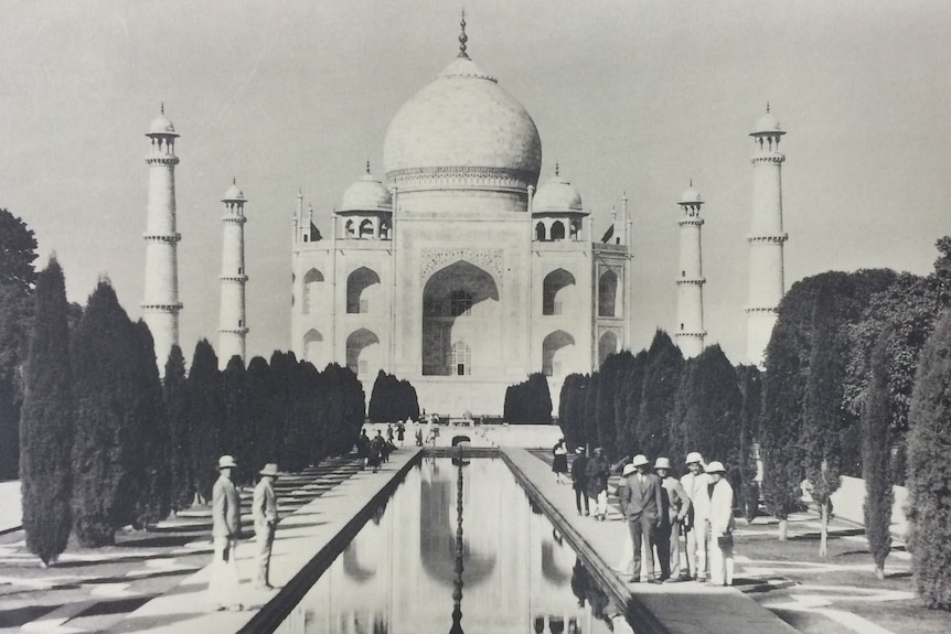 Black and white photograph of the Taj Mahal in the 1920s. Students are on either side of a pond in front of it.