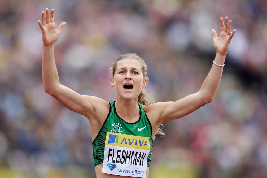 Pelari Lauren Fleshman mengangkat tangannya ke udara setelah balapan