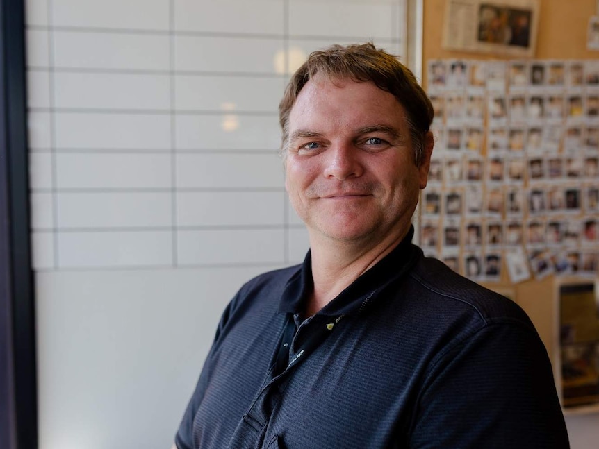 Man stands in a cafe and looks directly into the camera