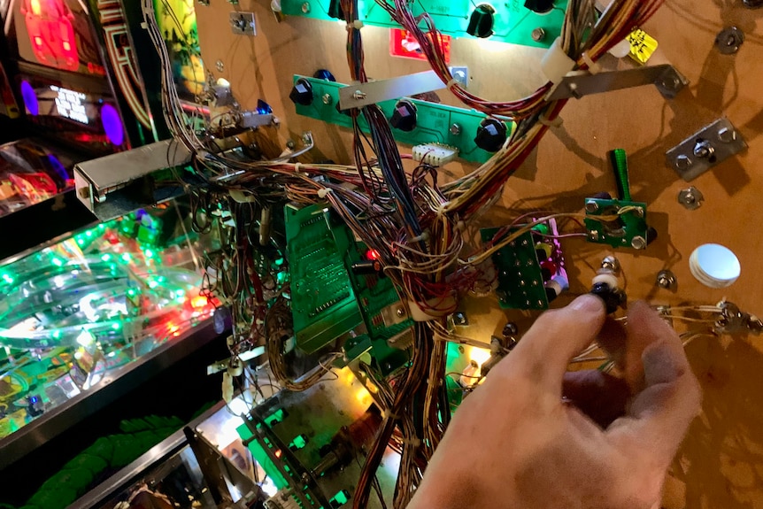 A hand and wiring inside a pinball machine 
