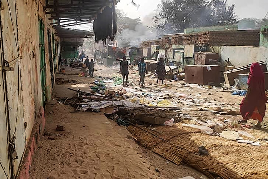 A low-quality photo shows people walking on a street covered in debris in the daytime.