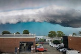 An angry-looking storm cloud looms over a suburb.
