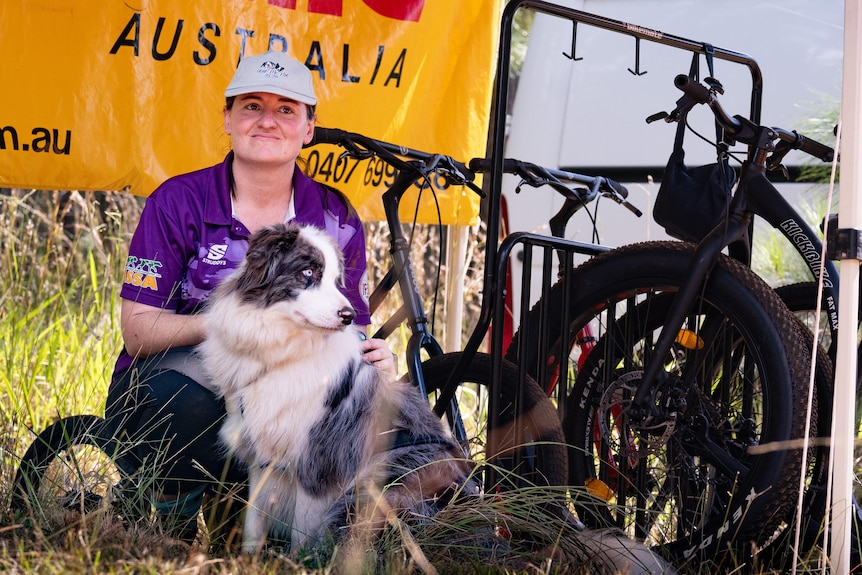 A woman and her dog sit next to some bicycles.