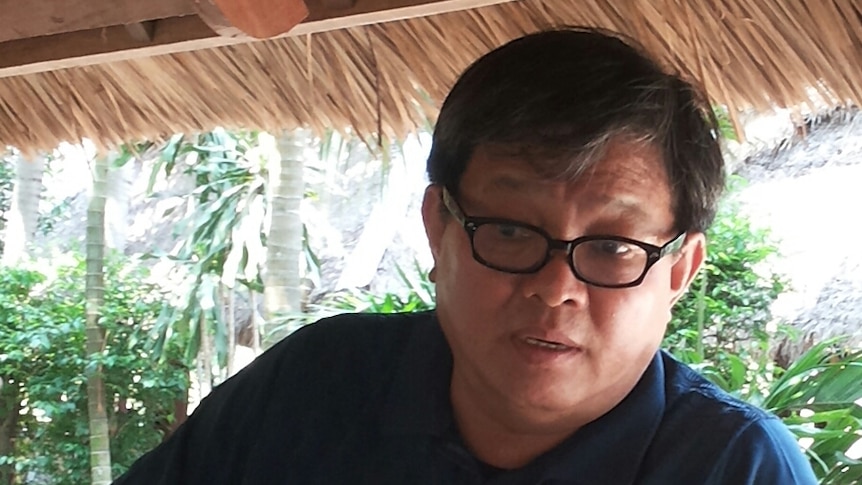 A man standing wearing glasses and a blue polo shirt 