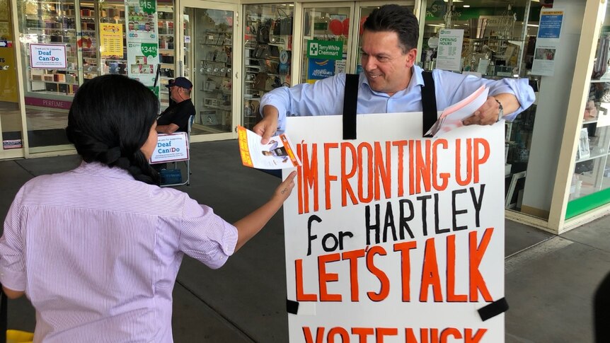 Nick Xenophon hands a campaign pamphlet to a voter at shops.