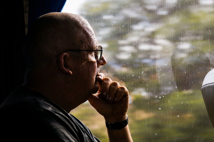 An older man looking out a bus window.