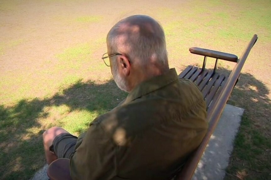 A man sits at a park bench