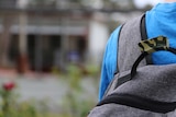 An unidentified child is seen outside a school with a backpack