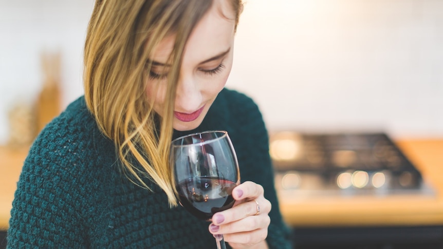 Woman holding wine red glass for story on how to limit alcohol consumption during coronavirus isolation