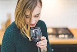 Woman holding wine red glass for story on how to limit alcohol consumption during coronavirus isolation