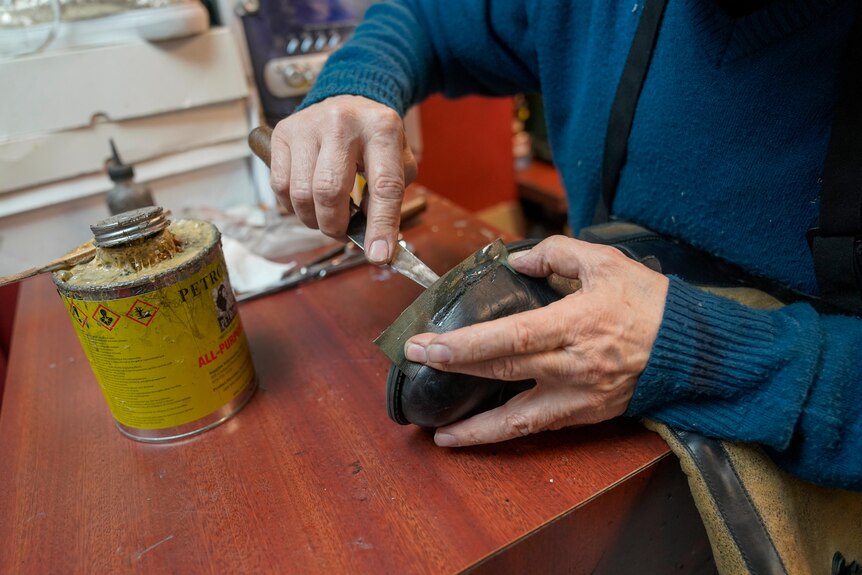 A close up of a man repairing a boot
