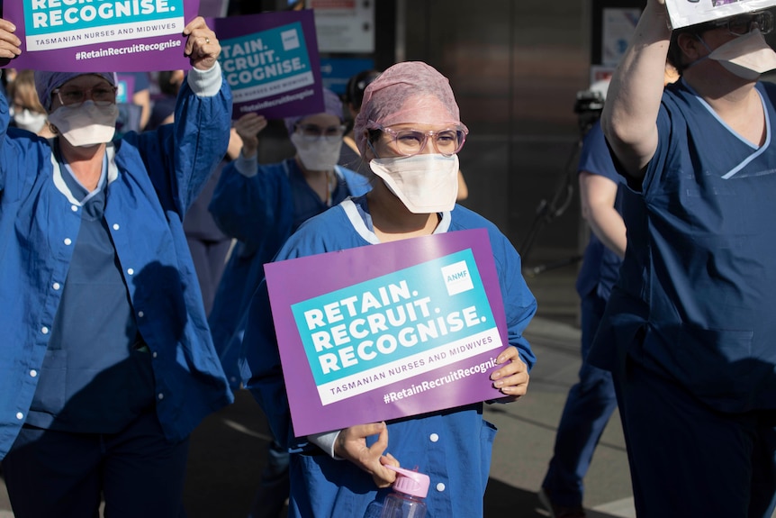 Nurses protest in Hobart, holding signs that say "retain, recruit, reorganise".