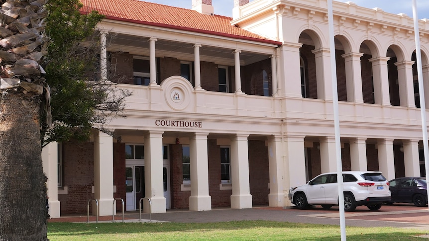 Exterior of Geraldton court house, flag poles with grass