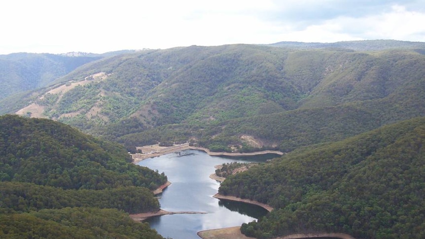 A dam surrounded by hills and trees.