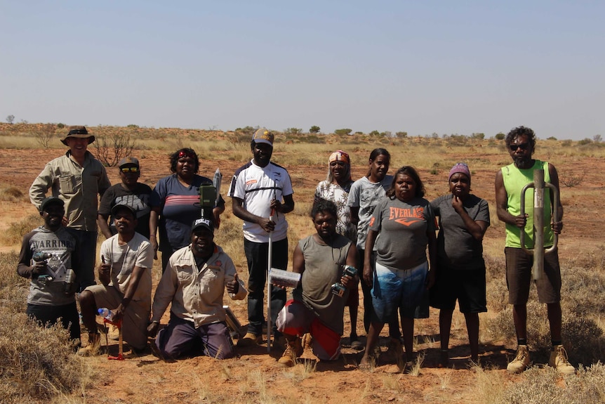 A group of people in casual clothing, in the desert, with a sound recording device.