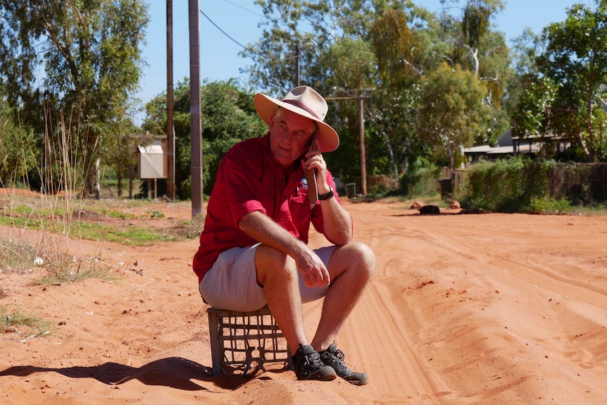 Alan Gray leans against a phone in a public phone booth in the Kimberley.