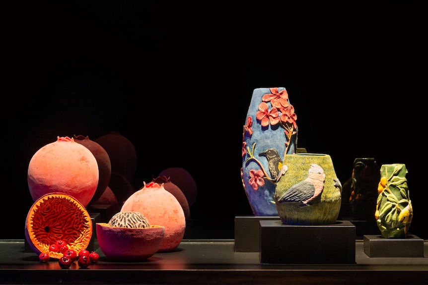 A collection of bright vases on plinths with a black background