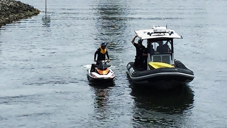 Police on a jetski and rubber inflatable search a Gold Coast canal for a missing kayaker.