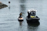 Police on a jetski and inside a rubber inflatable discuss their search on a Gold Coast canal