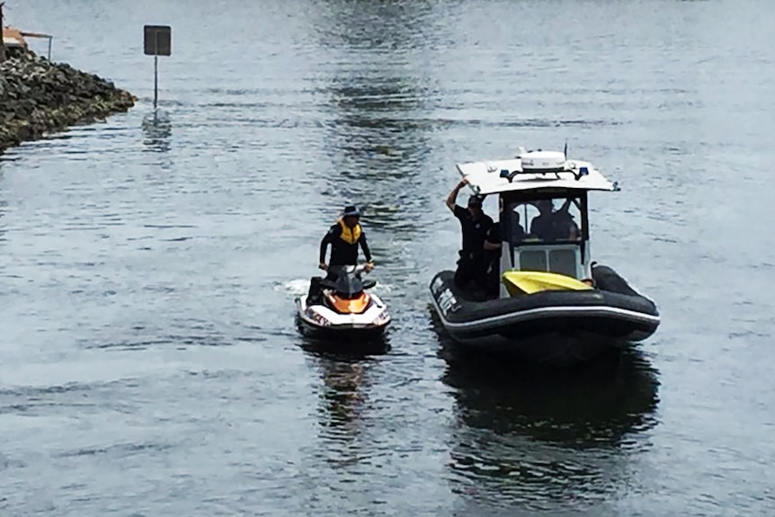Police on a jetski and inside a rubber inflatable discuss their search on a Gold Coast canal