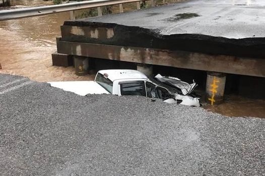 A collapsed bridge with a car in the river below