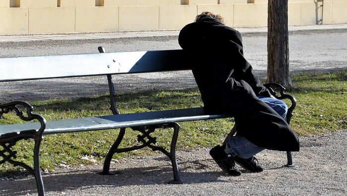 Unidentified homeless man slumped on a park bench.