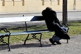 Unidentified homeless man slumped on a park bench.
